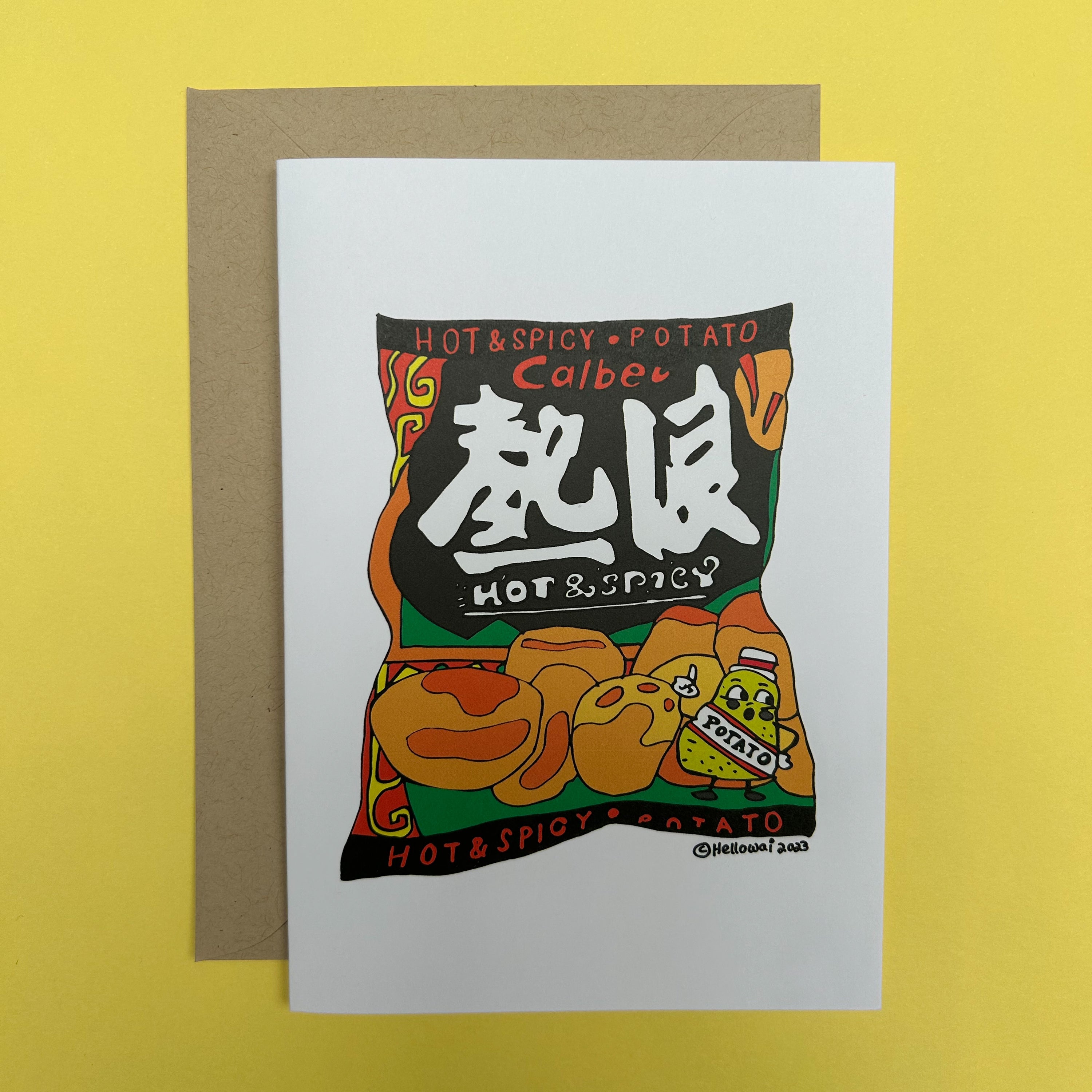 An A6 Hello Wai folded greeting card with a colour illustration of a bag of Calbee Hot and Spicy Potato chips, printed on white card. The card is placed on top of a brown envelope.