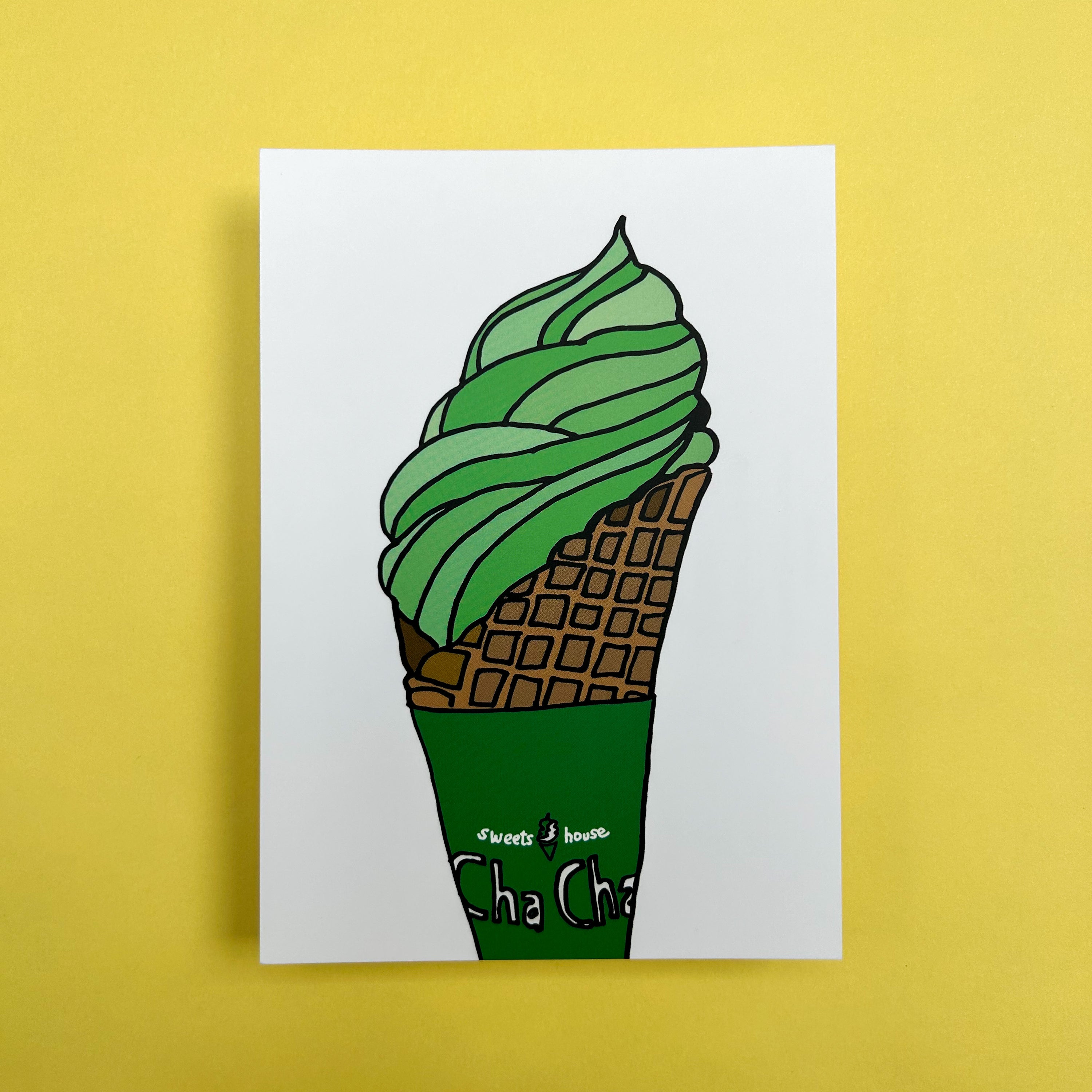 An A6 Hello Wai flat notecard with a colour illustration of a matcha flavoured soft serve ice cream in a waffle cone with a green cone wrapper, printed on white card. 